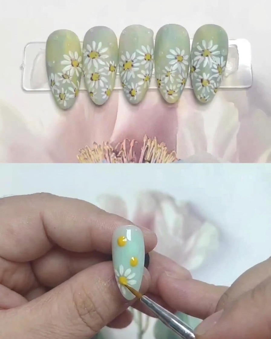 A brush applying a matte top coat over a completed daisy nail art design.