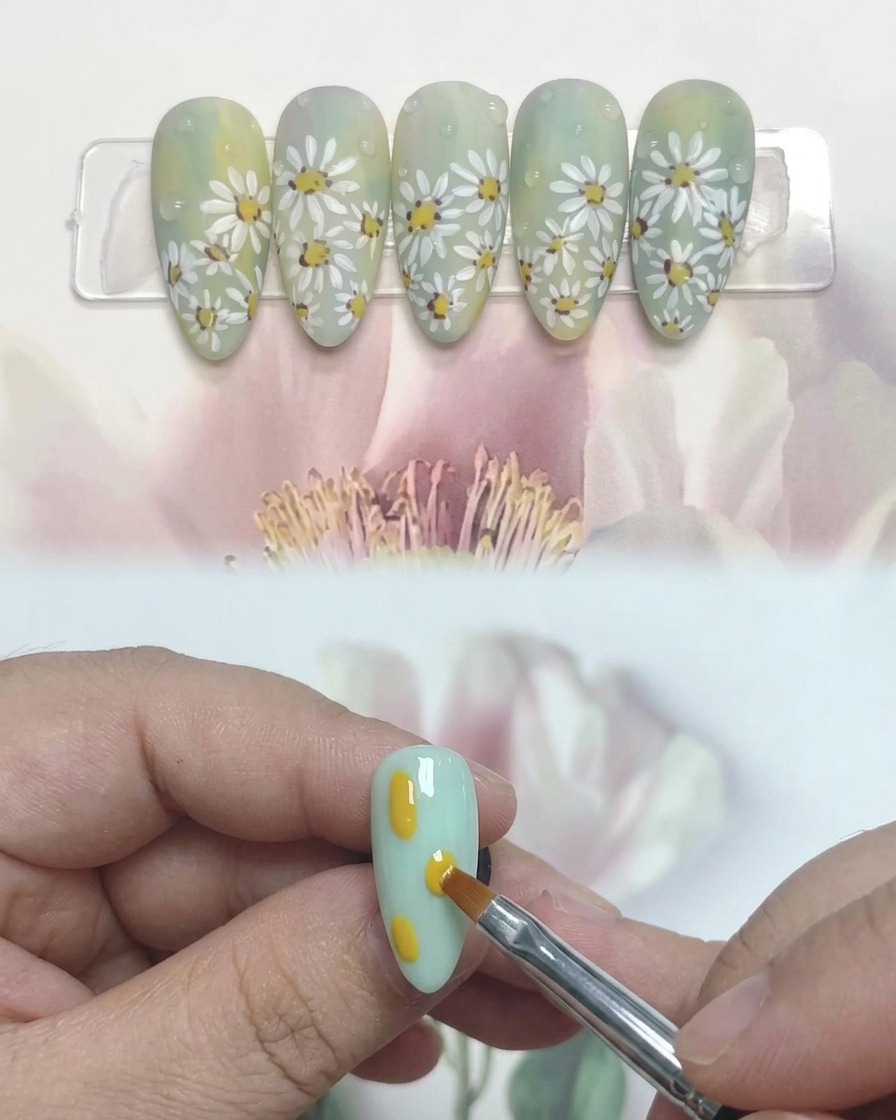 A close-up view of a hand with daisy-painted nails resting inside a professional UV nail lamp for curing.