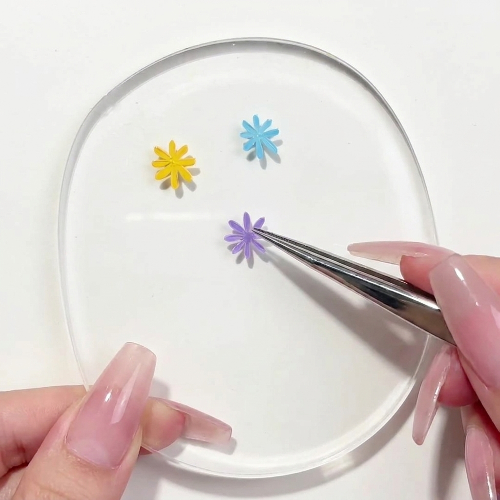A liner brush applying a second purple petal to the daisy design on the palette.