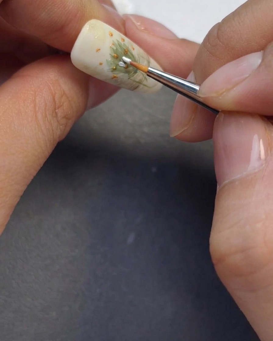 A fine brush painting delicate white daisy petals around the previously made flower centers.