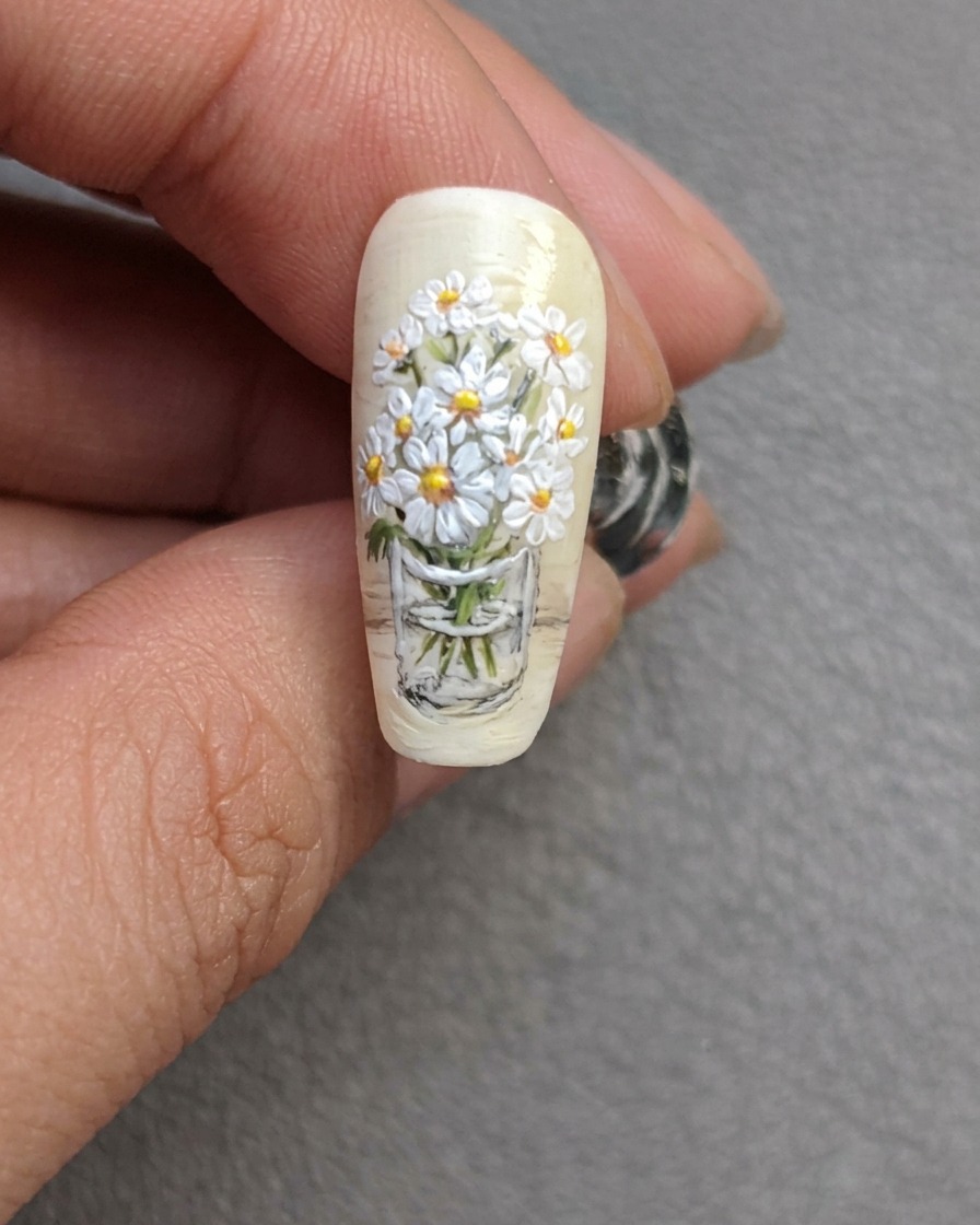Adding final, small green leaves to the daisy bouquet with a fine detail brush.