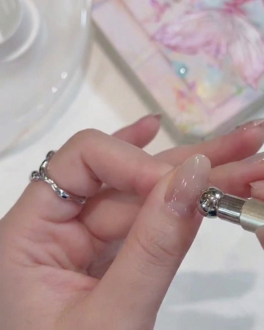 A close-up view of a hand with gel-coated nails placed under a compact UV lamp.