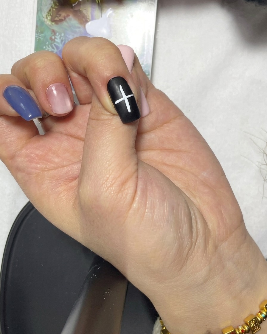 A close-up of a diagonal white line added to the existing cross shape on a black nail.