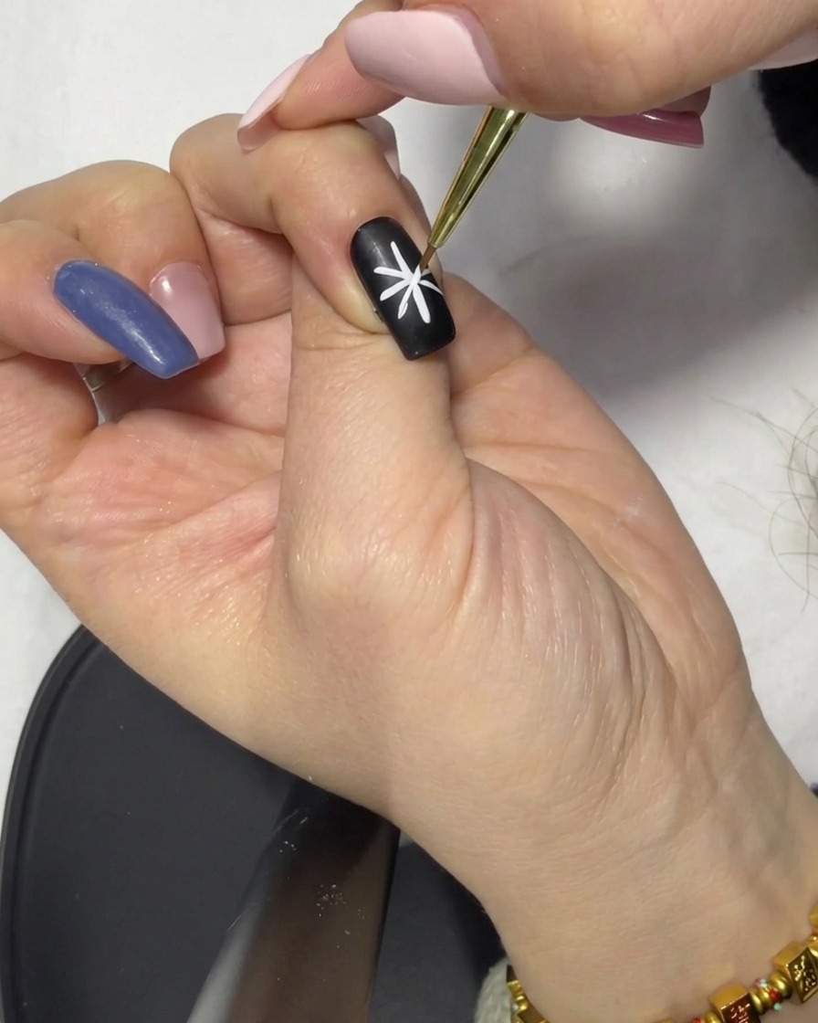 A close-up of a fine liner brush touching up one of the lines in the star design to ensure symmetry.