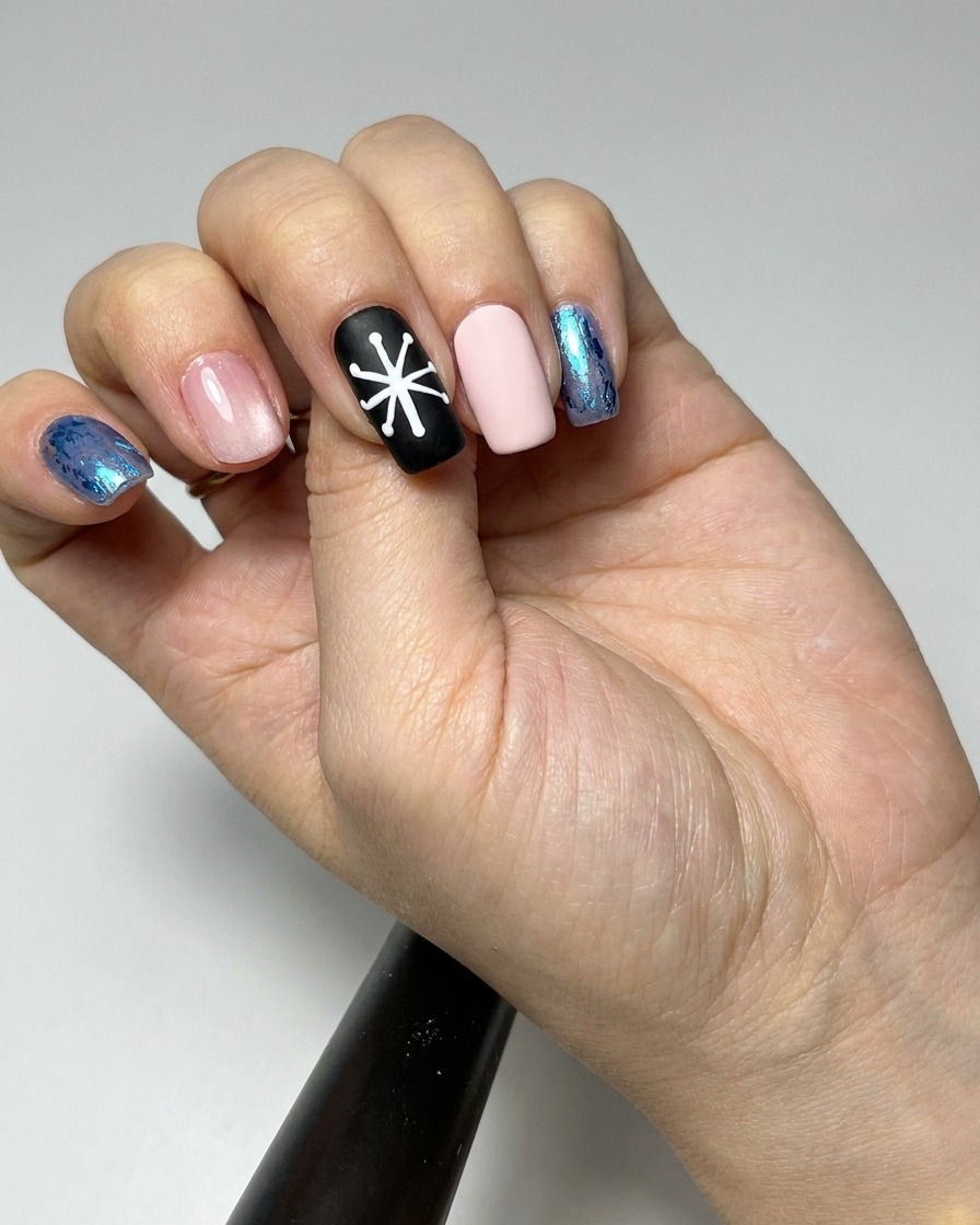 A liner brush filling in the petal sections of a daisy design on a black nail with white gel.