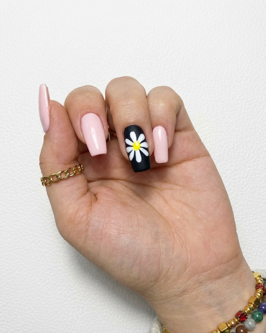 A completed white daisy design on a black nail with filled-in, opaque petals.
