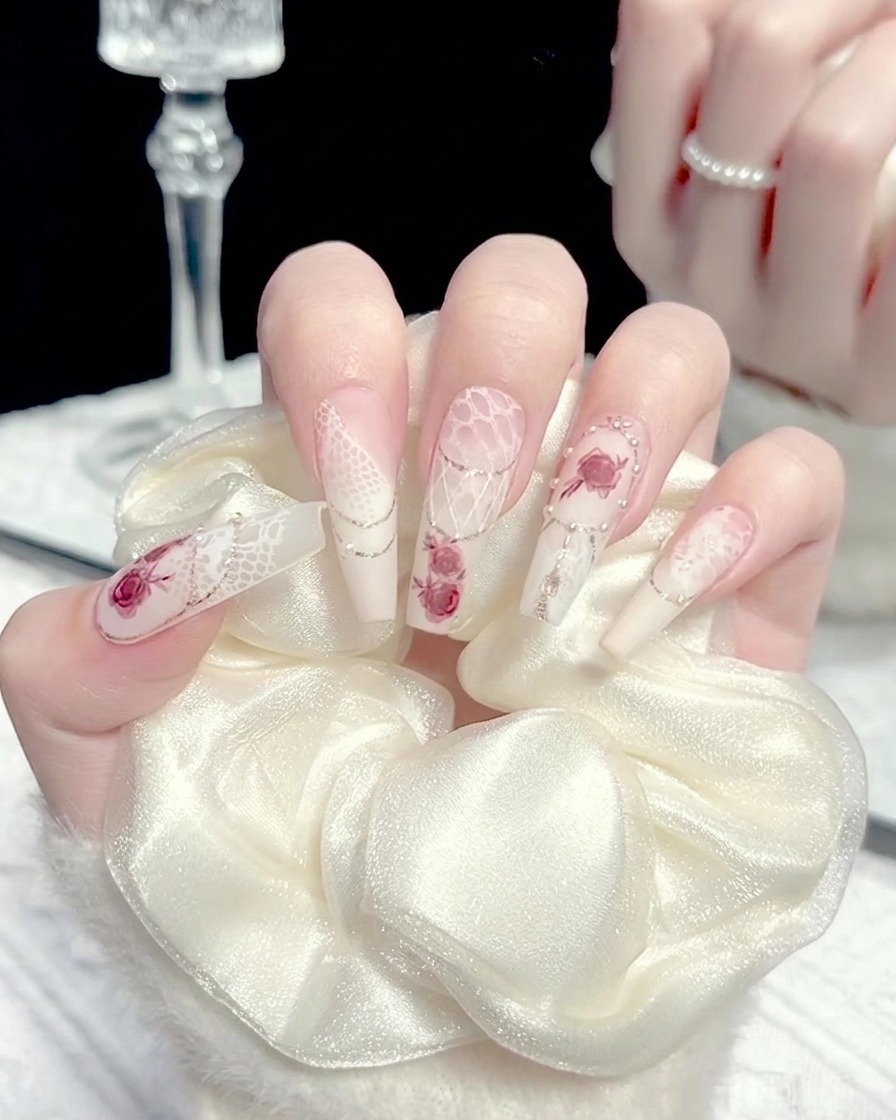 A brush applying a small amount of white gel to the center of a manicured nail.