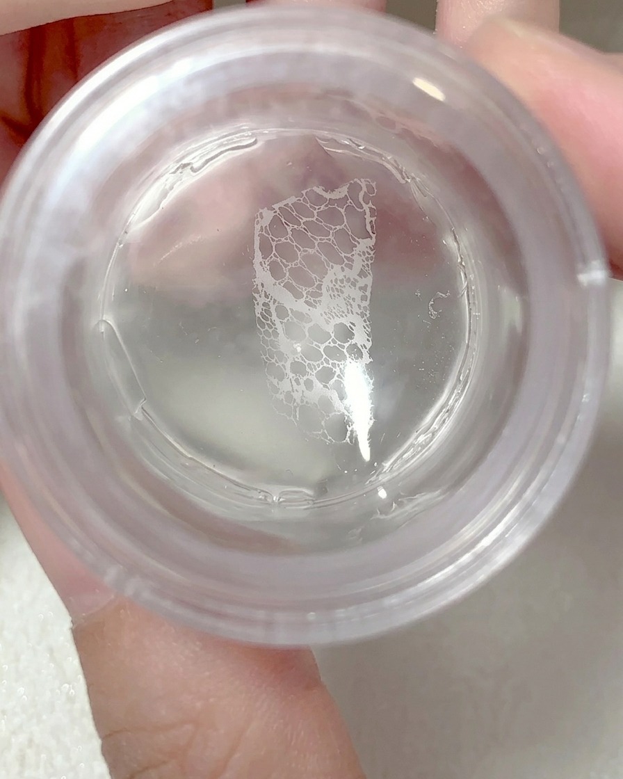 The silicone stamper being pressed onto a fingernail to transfer the lace design.