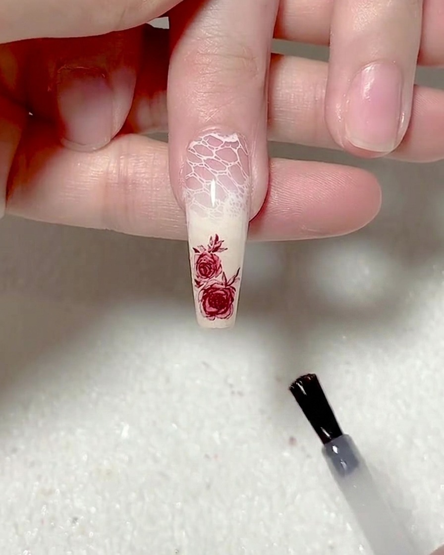A brush applying a smooth layer of matte top coat to the nail.