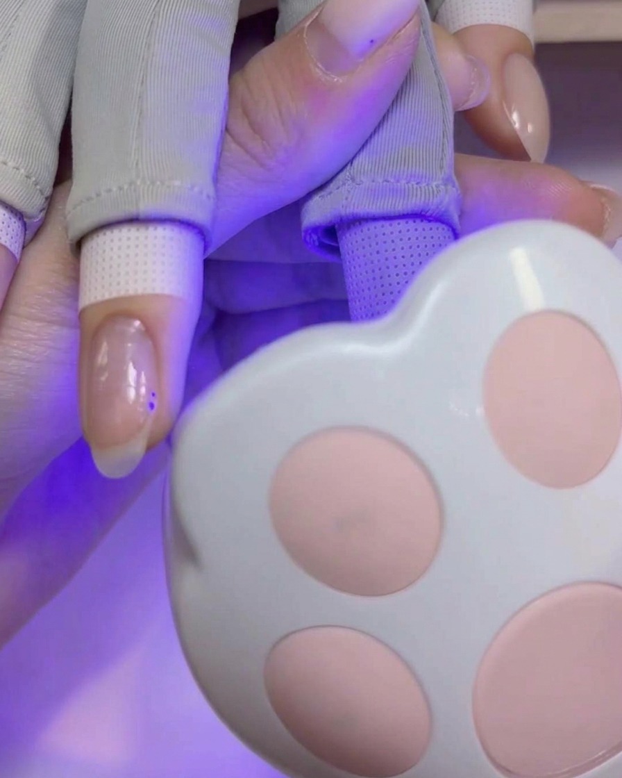A nail art brush applying a smooth, pigmented layer of builder gel onto the nail plate.