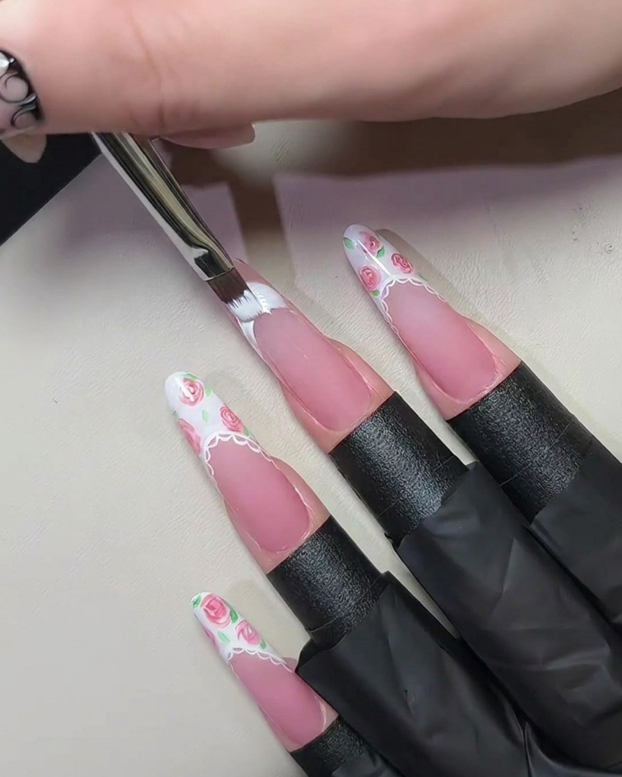 A close-up view of a hand with French tip nails positioned inside a UV/LED nail lamp during the curing process.