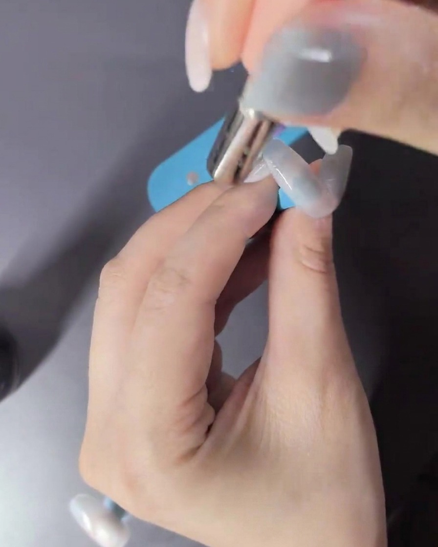 A hand inside an LED lamp curing the cat-eye gel polish.