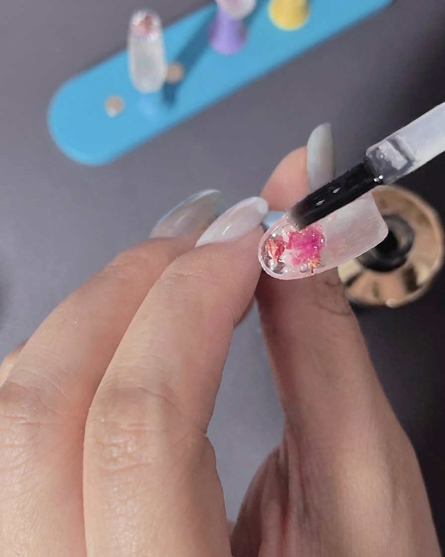 A hand placing a fingernail under the light of an LED nail curing lamp.