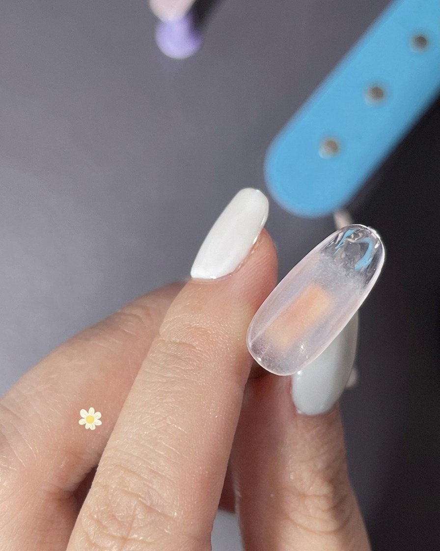 A close-up view of a clear gel layer being applied to a nail to prepare for a textured finish.