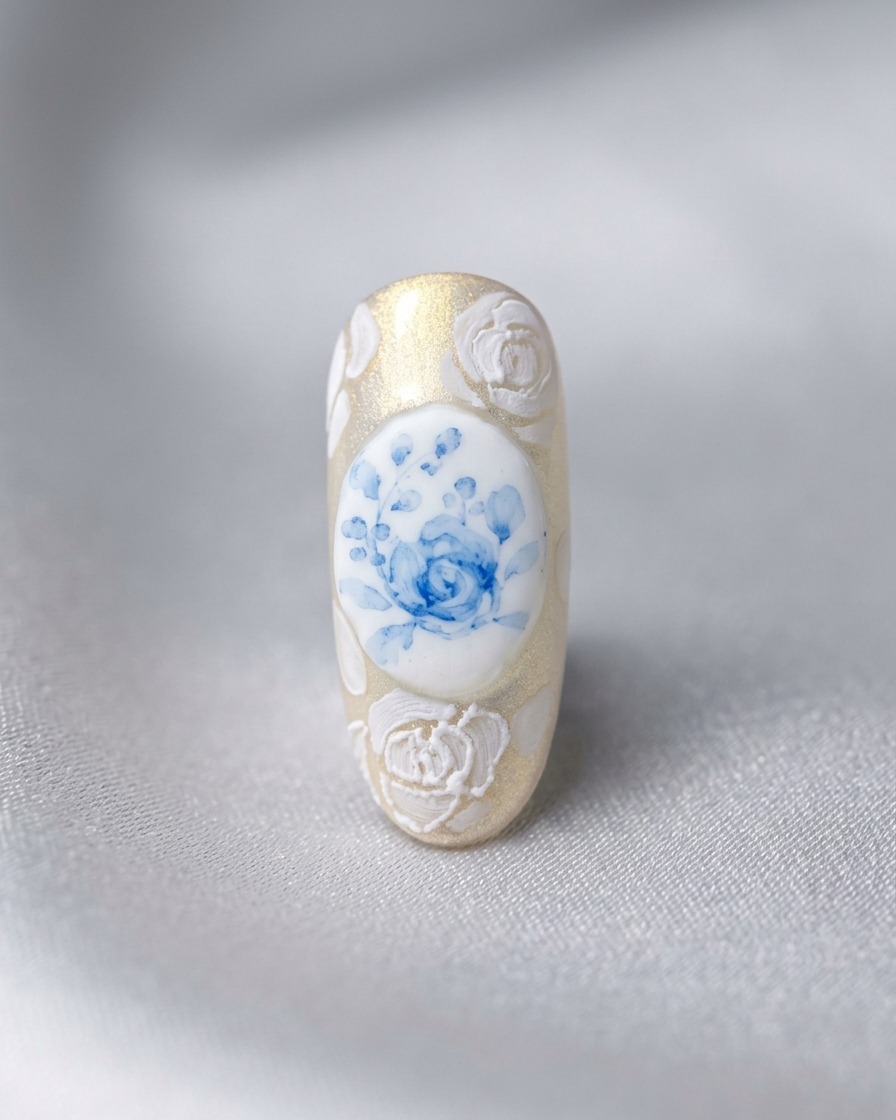A finished nail design featuring a central blue rose surrounded by 3D white roses and intricate lace work.