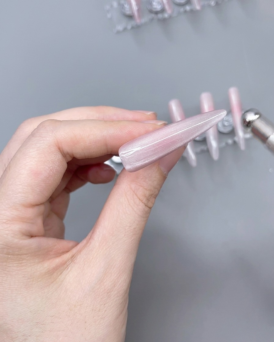 A magnet positioned over a nail tip coated in cat-eye gel to create a shimmer light effect.