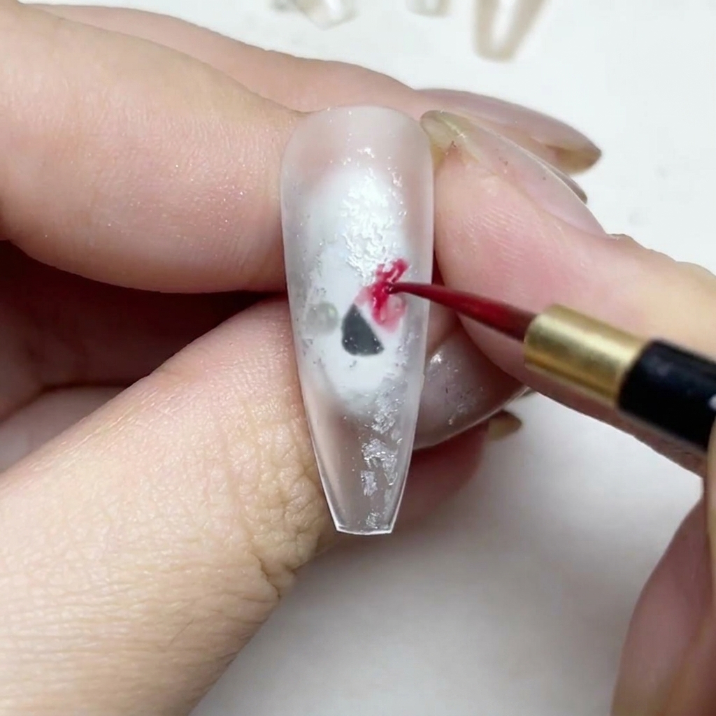 A fine liner brush painting red watercolor rose petals on a nail.