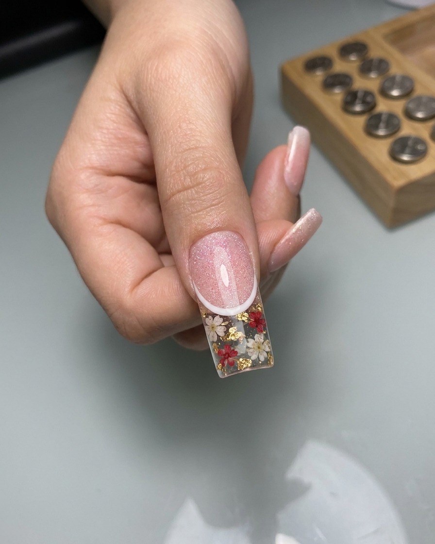 Close-up showing a fine liner brush drawing thin, white, lace-patterned lines over the cured cat-eye nail surface.