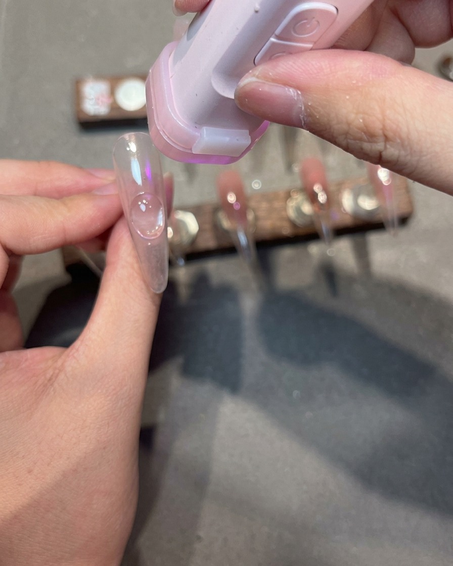 A nail tip with magnetic gel showing a diagonal shimmering light effect across the side of the nail.