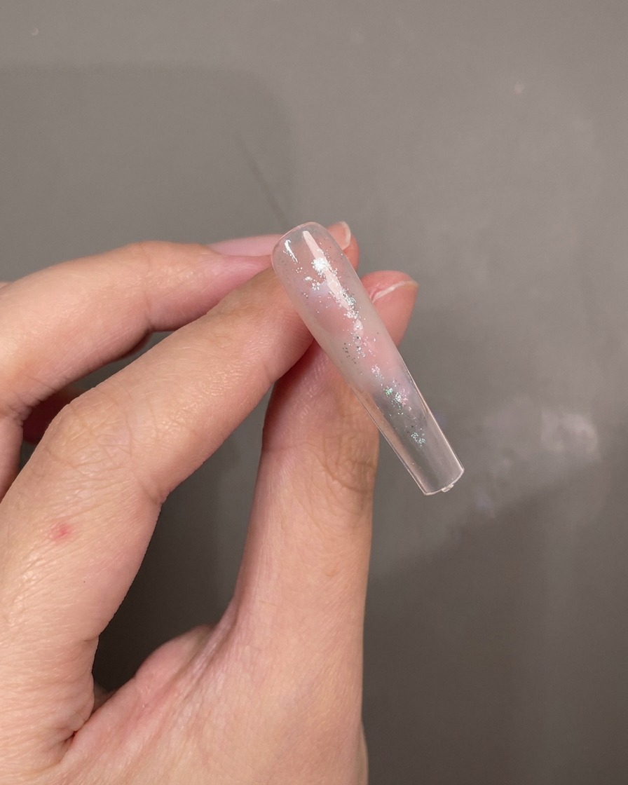 A brush dabbing blue cat-eye gel onto an abstractly painted nail tip.