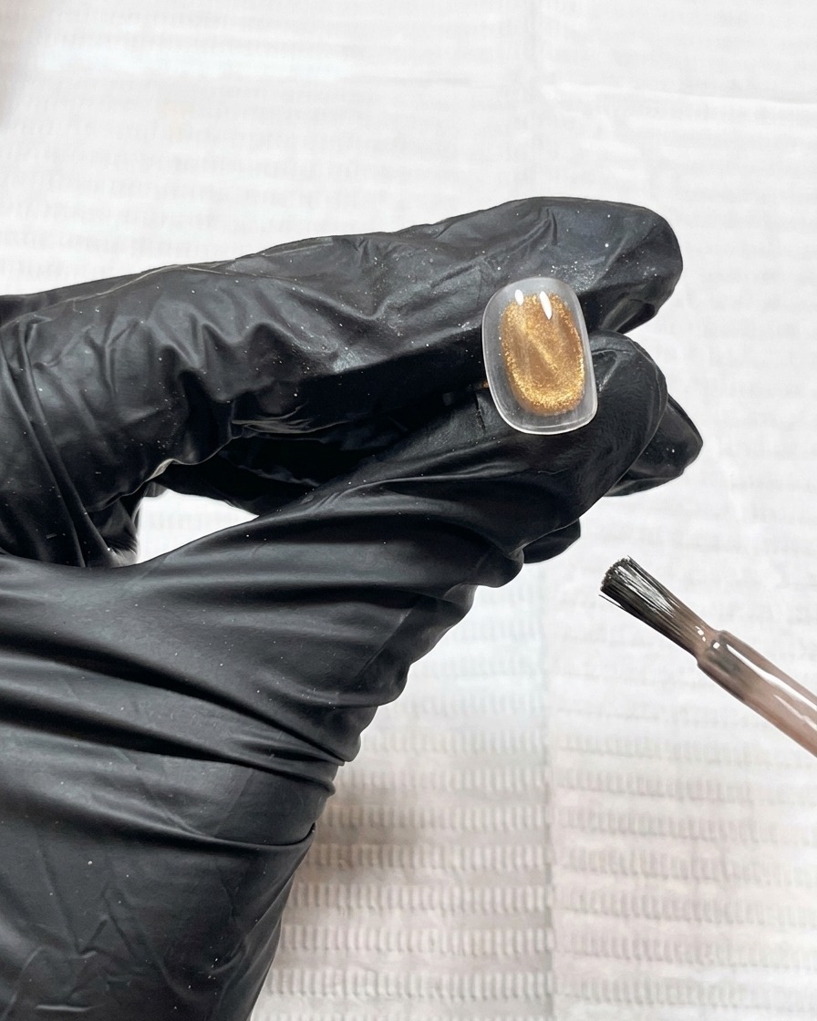 A close-up view of a nail tip coated in mauve cat-eye gel, showing a smooth, wet-look surface.