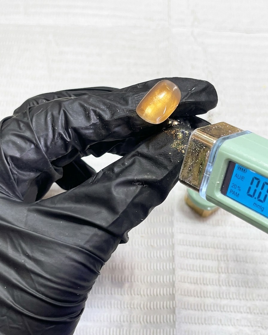 A fingernail being cured under a professional UV nail lamp.