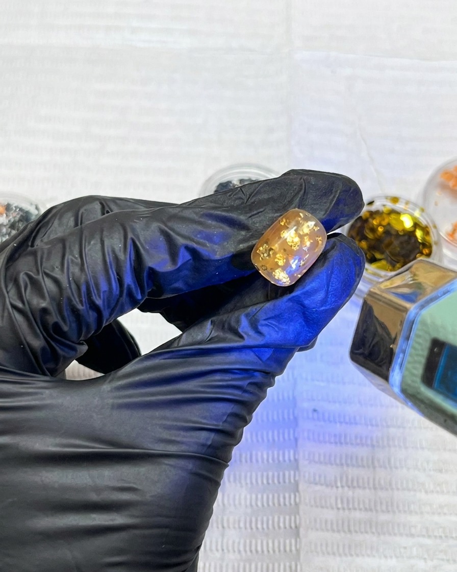 A single nail with floral art glowing under the blue light of a professional UV nail lamp.