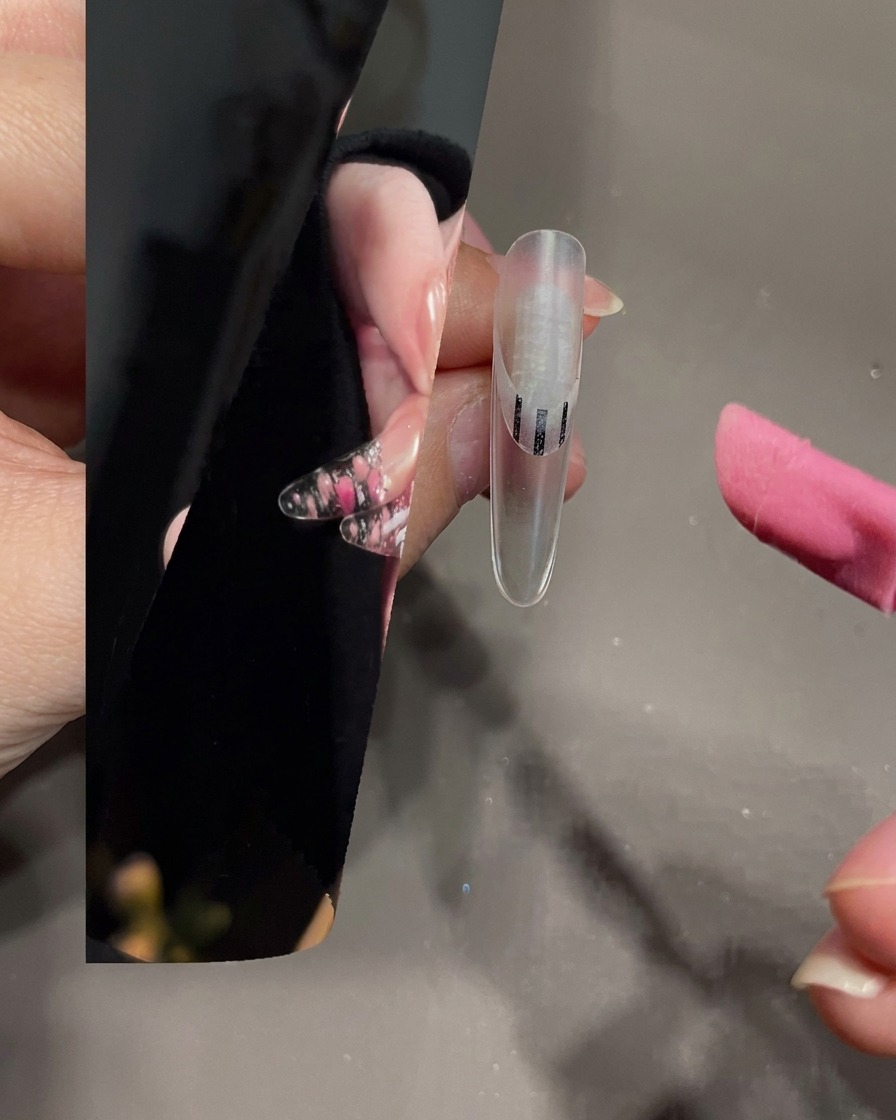 A nail brush spreading white gel onto the tip of a clear nail.