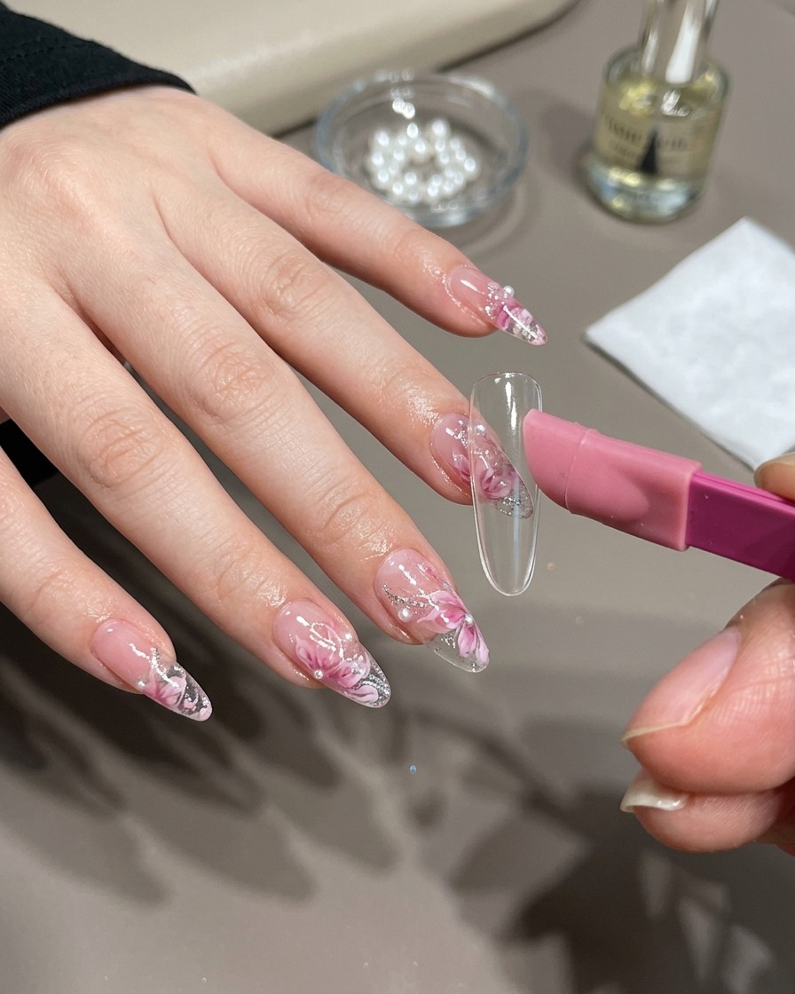 A nail brush applying golden magnetic gel over a nail tip.