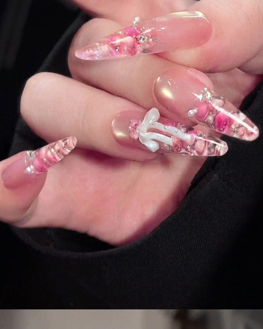 A close-up of a fine brush applying white gel detailing onto a pre-formed 3D gel bow.