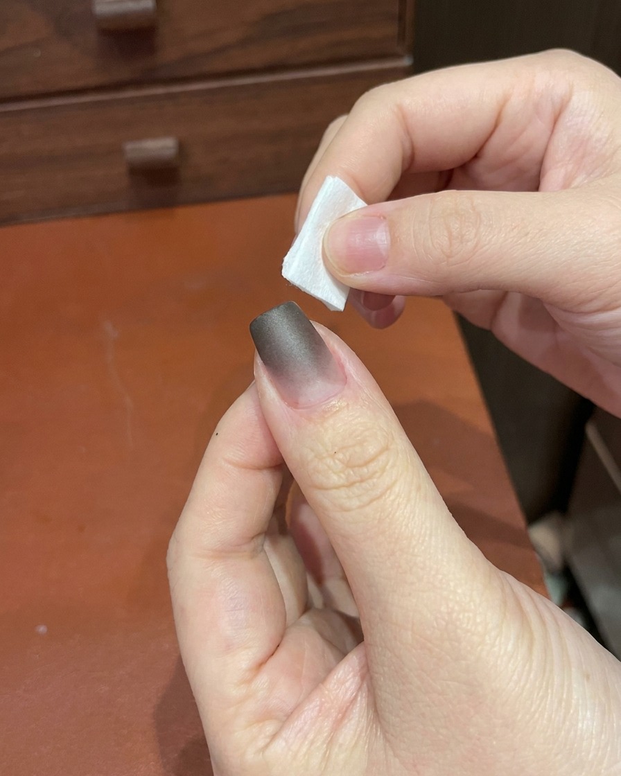 A hand placing a finger under a small, portable UV/LED nail lamp.