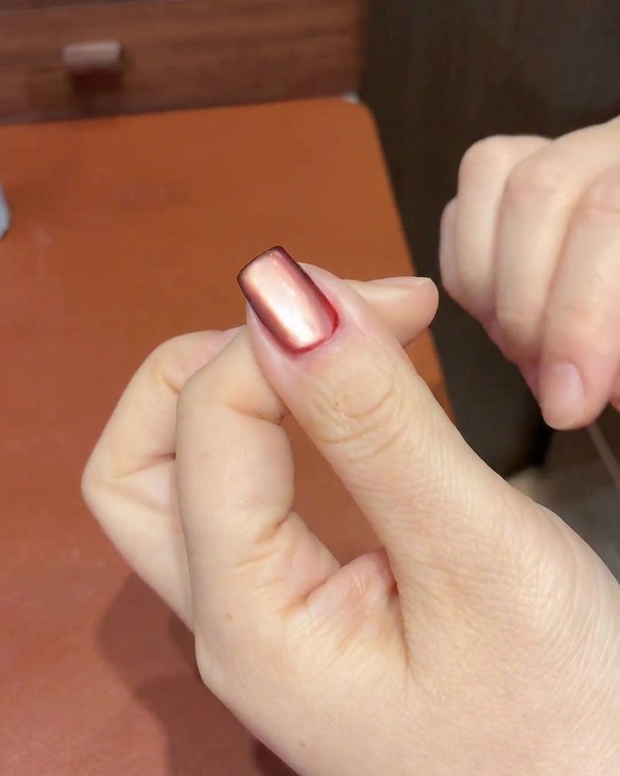 A magnet being used to pull and concentrate the cat-eye shimmer into a specific highlight area on the nail.