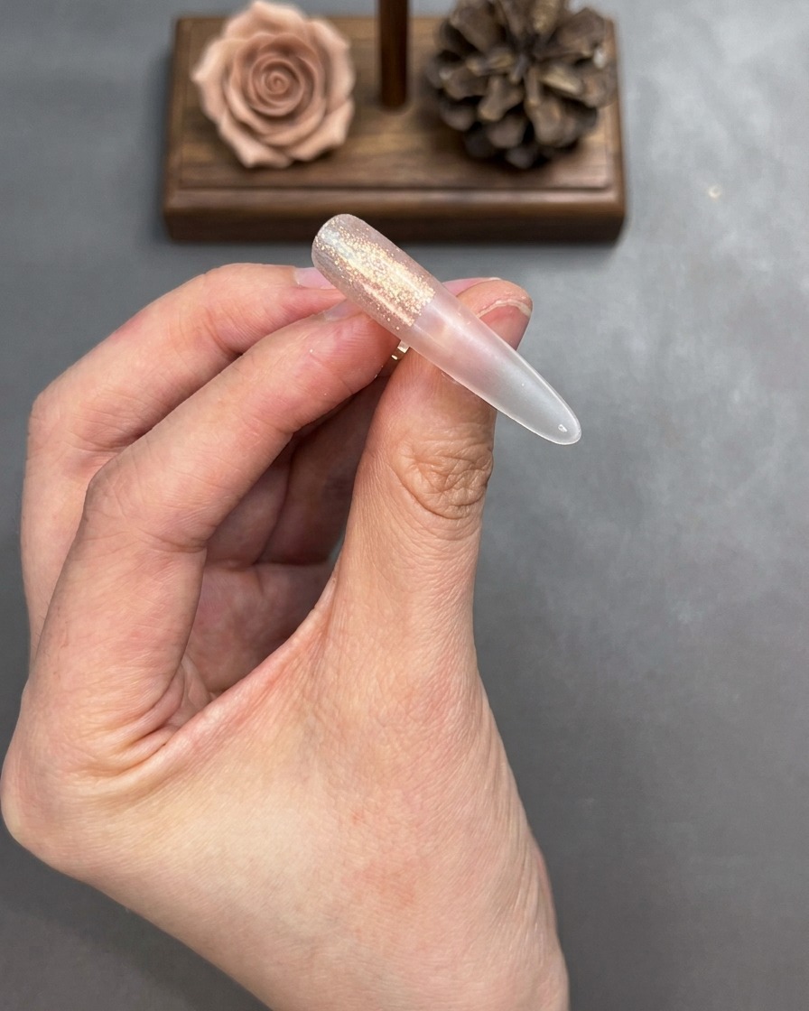 A brush blending the edges of the applied cat-eye gel on a nail tip to create a smooth transition.