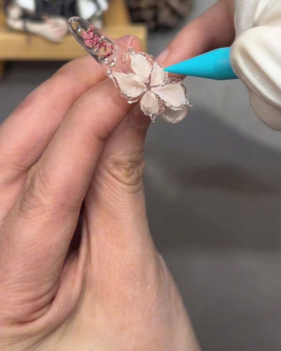 A close-up view of the flower design on the nail, now appearing glossy and translucent after applying clear jelly gel.