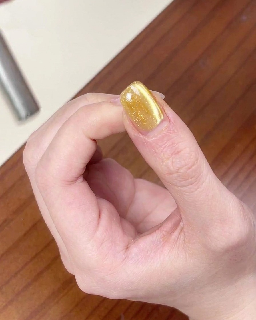 The magnet being used to pull magnetic particles to create a wider cat-eye shimmer on the nail.