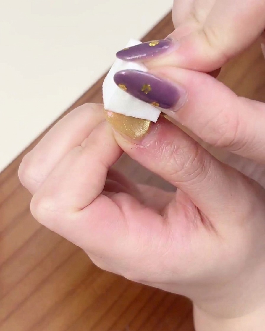 A hand positioned under a professional UV/LED nail lamp for curing the gradient gel layer.