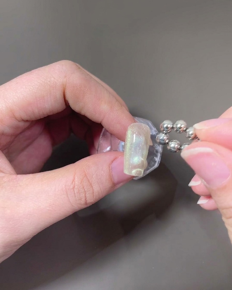 A ball-tipped magnet being used to create wave patterns on the wet cat-eye gel.