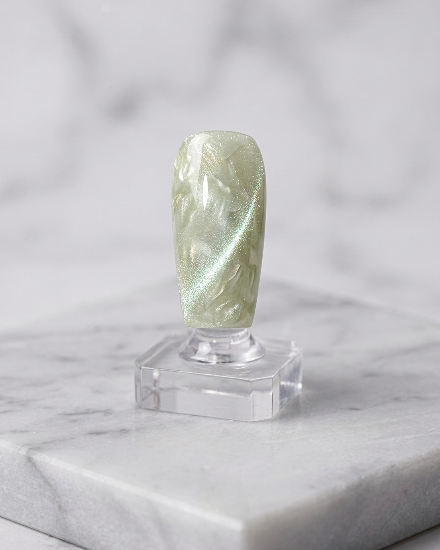 A nail brush applying a second layer of cat-eye gel over the cured base.
