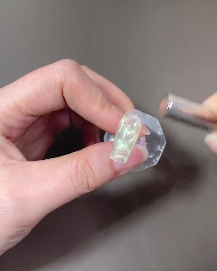 A rectangular magnet being used to form a wide cat-eye light on the second layer of gel.