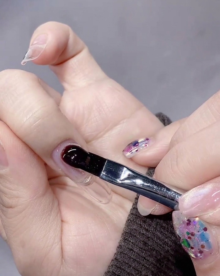 A brush placing a large, controlled bead of builder gel near the cuticle of the nail.