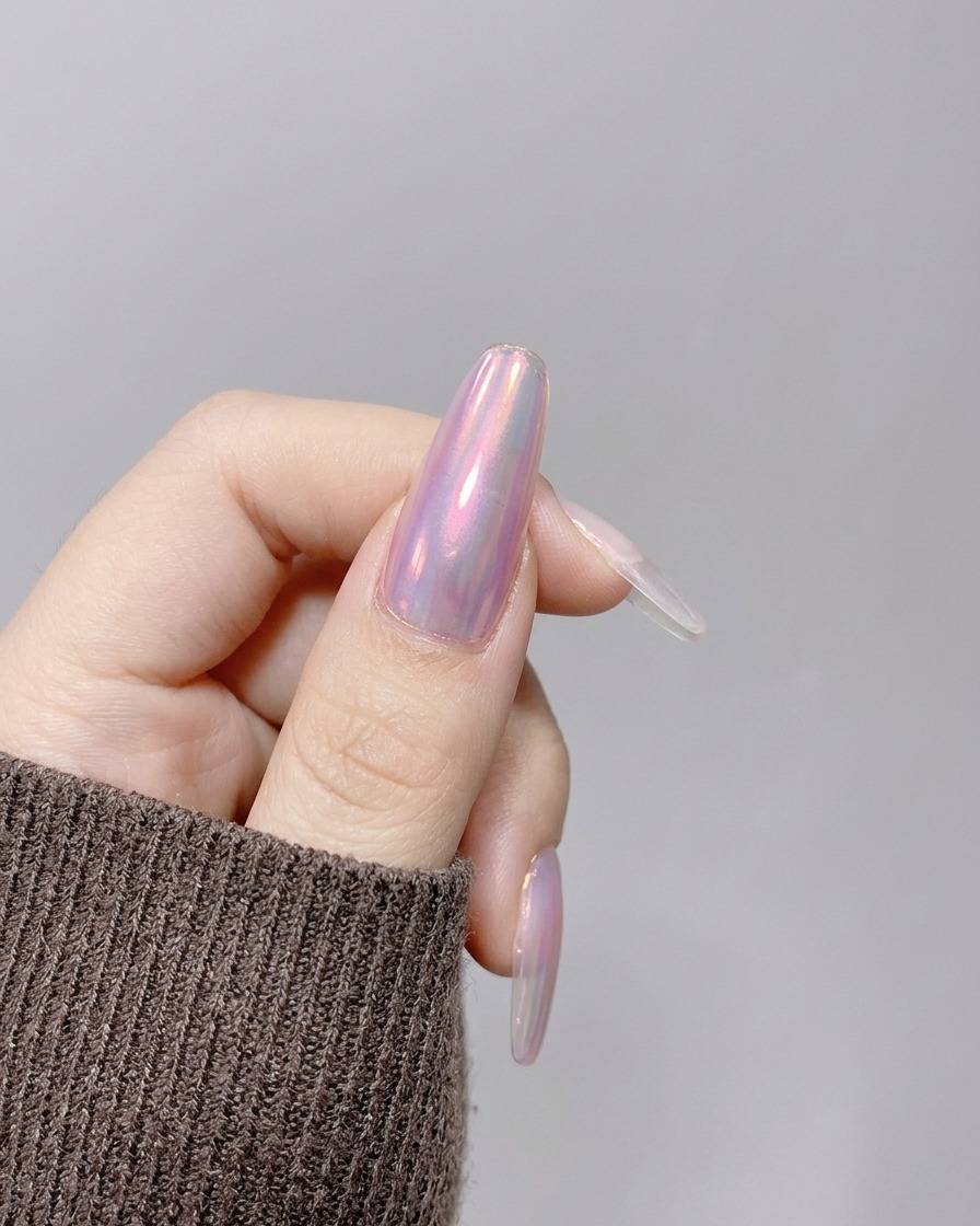 A hand positioned under a compact, handheld pink UV/LED lamp to cure the nail enhancement.