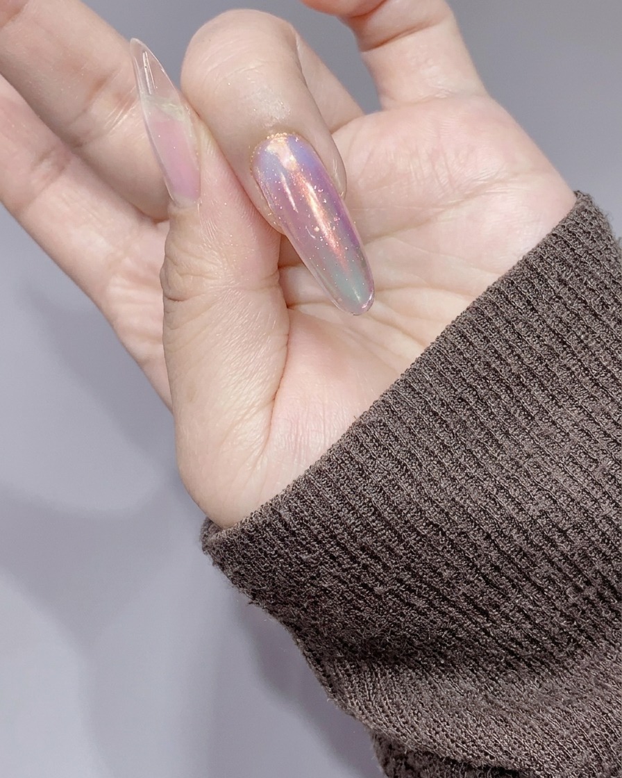 The nails being cured under a small pink UV/LED lamp after the application of silver glitter gel.