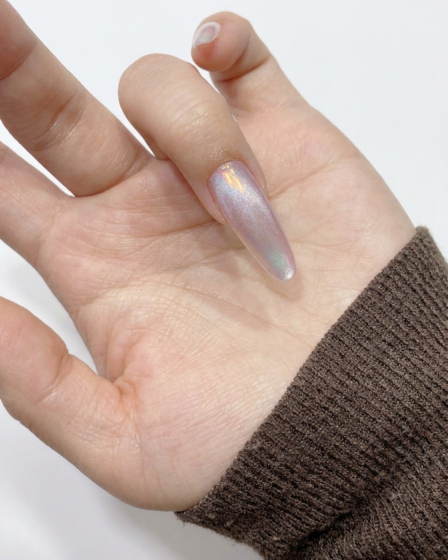 A cylindrical magnet held against the side of a nail, drawing the magnetic shimmer toward the edge.