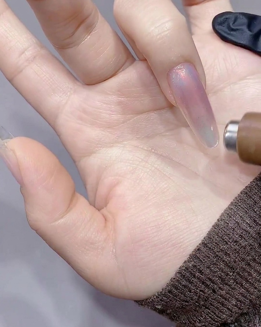 The cylindrical magnet being pulled along the right side of the nail, creating a sharp line of light.
