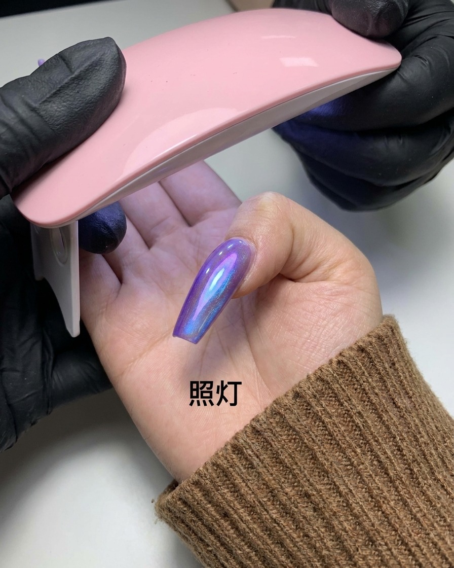 A finger with the completed magnetic cat-eye pattern being held under a small pink UV/LED nail lamp.