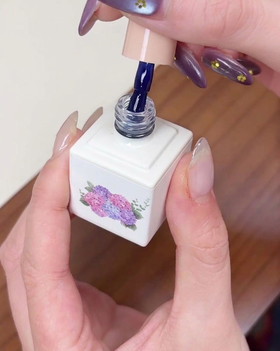 A brush applying dark blue gel polish onto a prepped nail, ensuring even coverage.