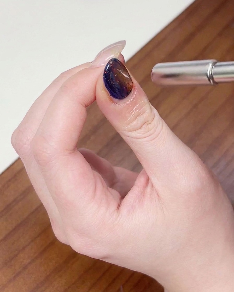 A magnet being moved in a circular motion around the nail tip to shape the cat eye shimmer.