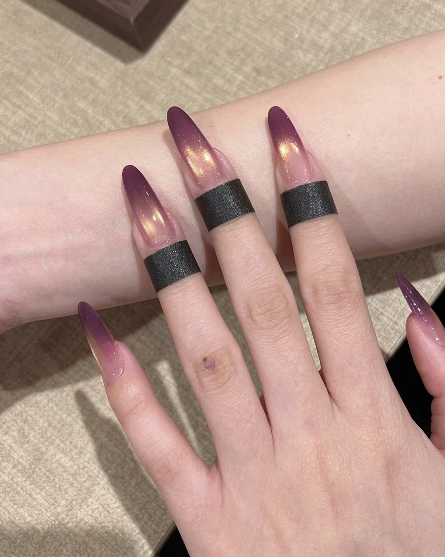 A hand with ombre-painted nails positioned inside a professional UV nail lamp for curing.