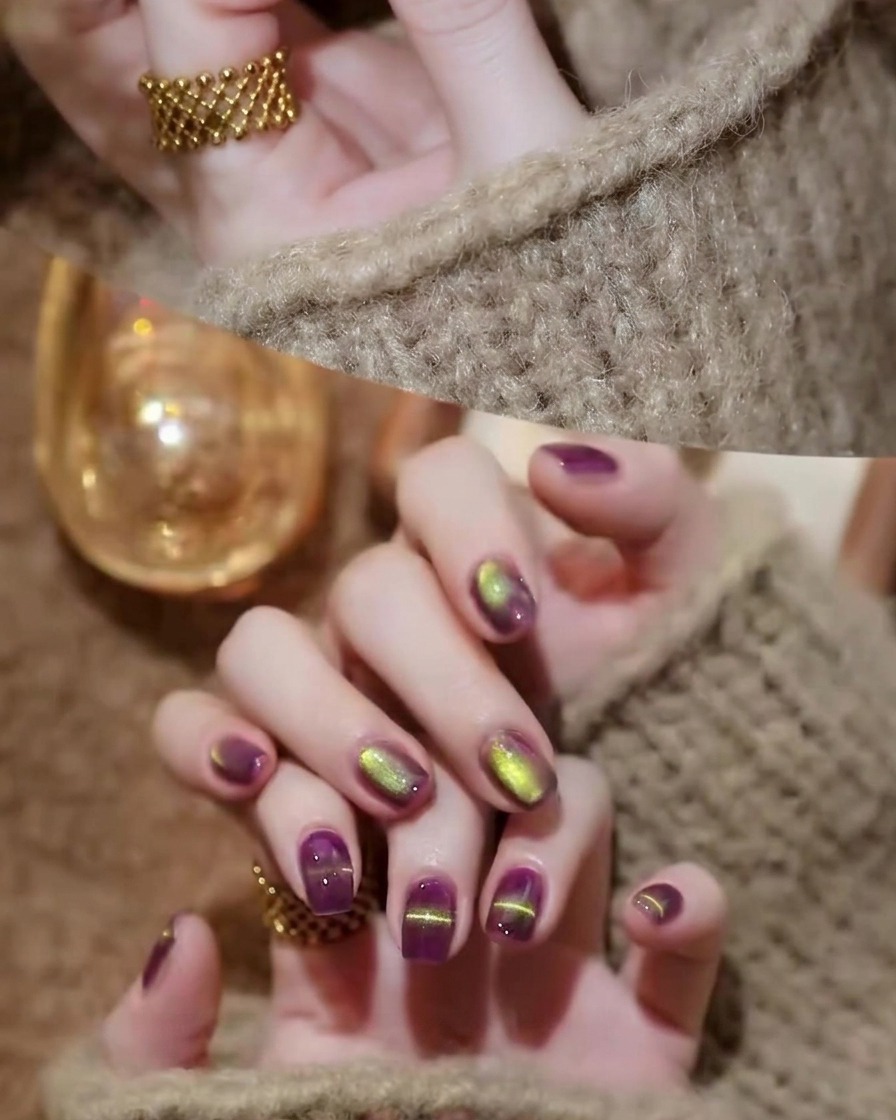 A nail brush applying a clear, glossy top coat over the cured purple and gold cat-eye nails.