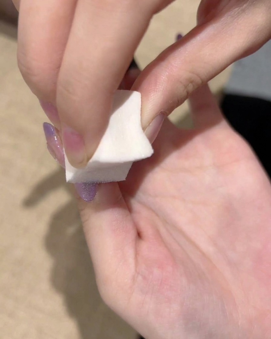 A close-up of a sponge repeatedly patting the purple gel edge to finalize a smooth gradient transition.